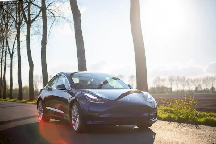 Tesla electric car driving on a rural road representing innovation in electric vehicles and sustainable transportation