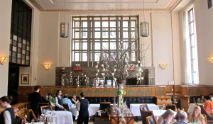 Interior dining room of Eleven Madison Park with high ceilings, white tablecloth tables, and staff serving guests