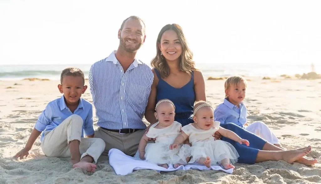 Nick Vujicic with his wife Kanae and their children on a beach, reflecting the family foundation behind his message of resilience and purpose.