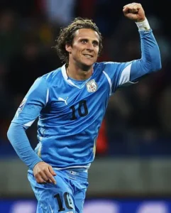 Diego Forlán celebrating with raised fist in Uruguay uniform - Diego Forlán World Cup peak | Aurum Speakers Bureau
