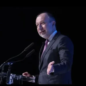 Jorge Guajardo speaking on stage at a podium about supply chain risk and geopolitics - supply chain weaponization | Aurum Speakers Bureau